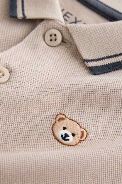 Stone polo shirt close-up: button placket and embroidered bear on chest