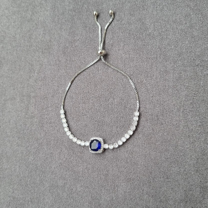 Adjustable beaded bracelet featuring round sapphire-blue crystal centerpiece