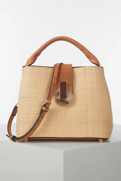 Tan woven handbag with brown leather top handle, front clasp, and crossbody strap