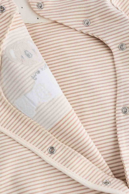 Baby striped romper close-up with cream trim and round snap fasteners