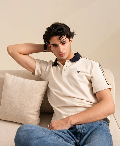 Fitted off-white polo shirt with navy collar and button placket; laid-back fit.