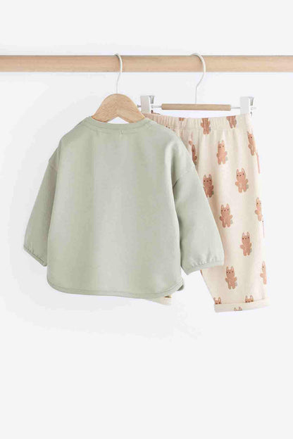 Sage green long-sleeve top back and cream bunny print shorts set on hangers