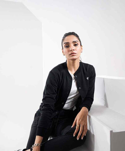Black button-front fitted jacket with long sleeves and chest logo, paired with dark pants