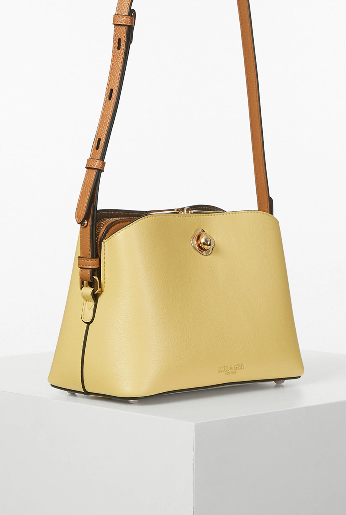 Yellow crossbody bag with top handle and gold clasp, brown leather trim