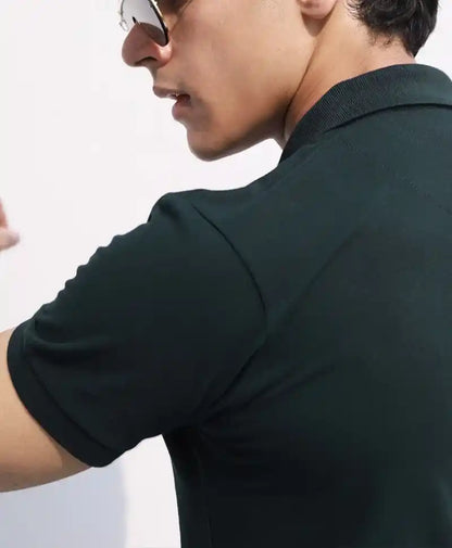 Close-up of fitted dark green polo shirt collar and short sleeves, small logo on chest