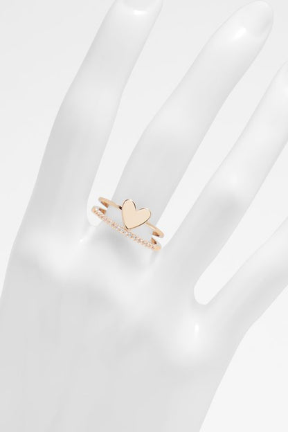 Gold-tone heart ring with clear stones, worn on a hand with finger gap