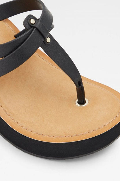 Black cross-strap sandal with tan footbed and metal ring detail