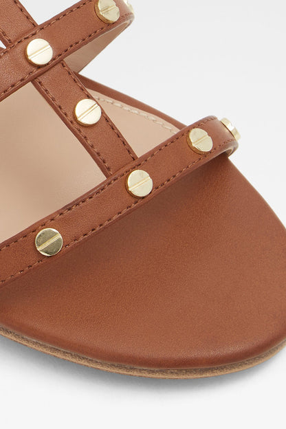 Cognac sandal strap close-up with round gold-tone studs and stitching