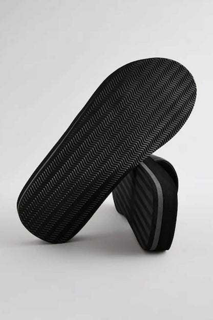Black slide sandals with textured outsole tread and curved midsole