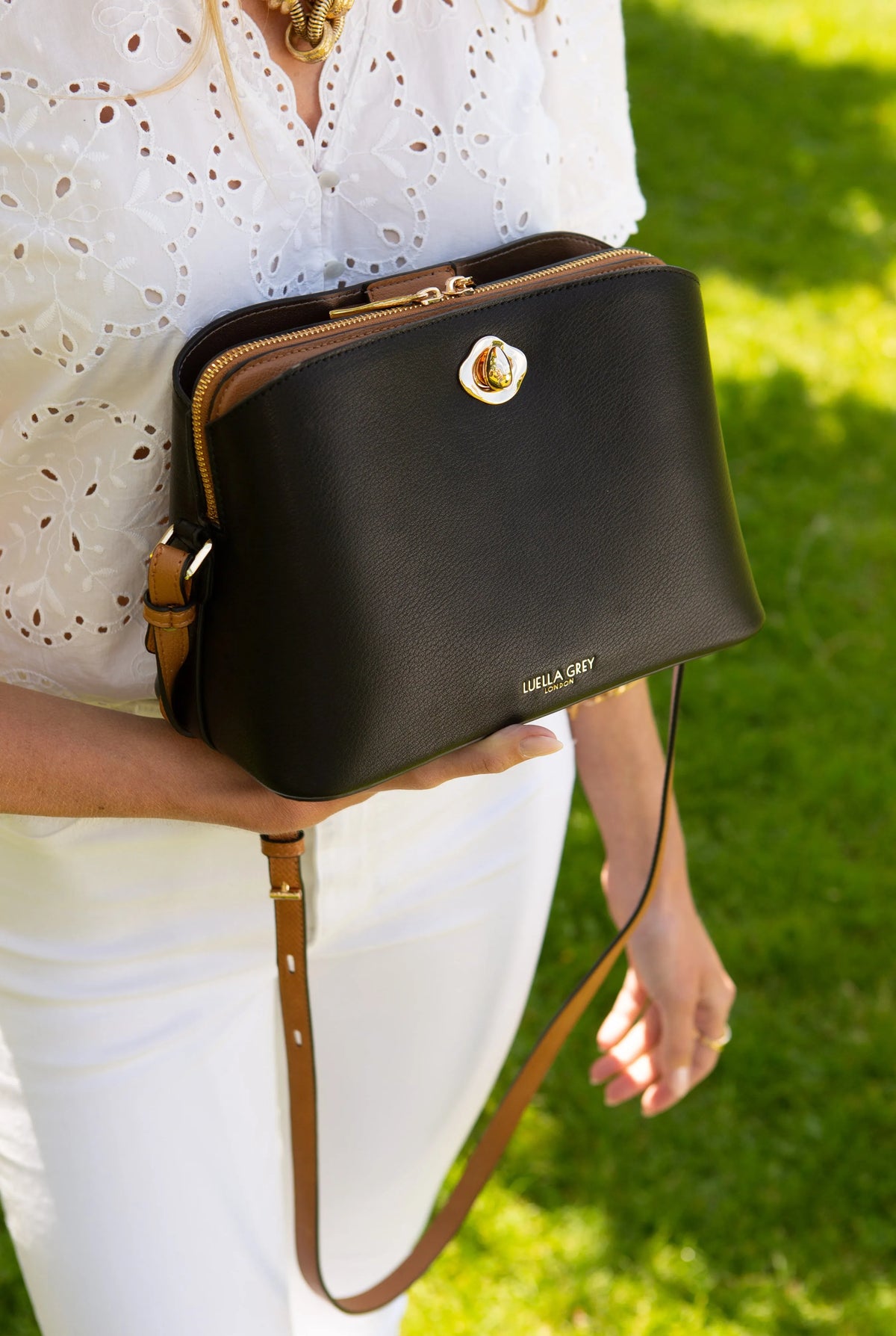 Black mini crossbody bag close-up with gold twist-lock clasp and top zipper