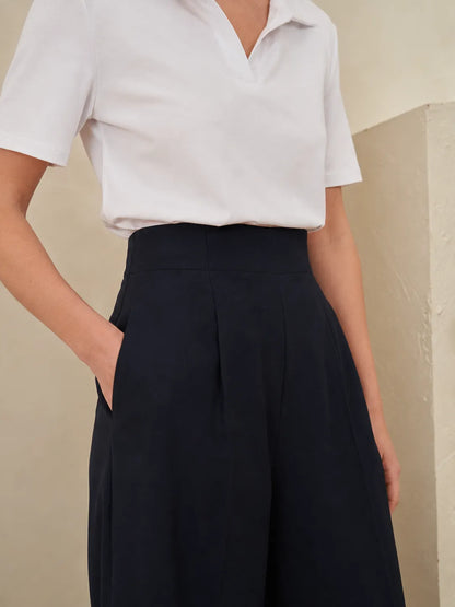 White short-sleeve blouse with pointed collar; dark high-waist trousers