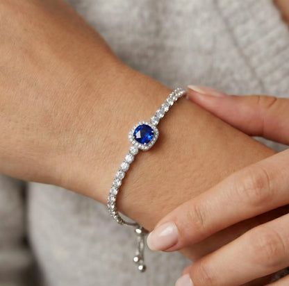 Silver-tone beaded bracelet on wrist with round blue crystal centerpiece