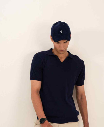 Navy fitted baseball cap with small white logo, front view on model.