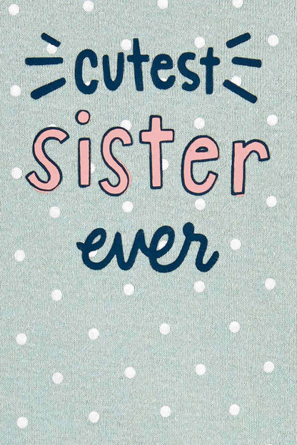 Light green bodysuit fabric close-up with “Cutest Sister ever” colorful text and white dots