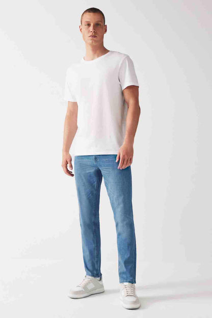 Light blue denim jeans on model with tapered legs and stitched front pockets