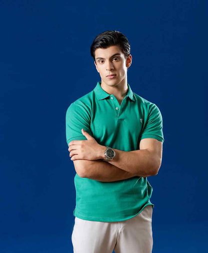 Fitted green polo shirt with short sleeves and buttoned collar, chest logo detail