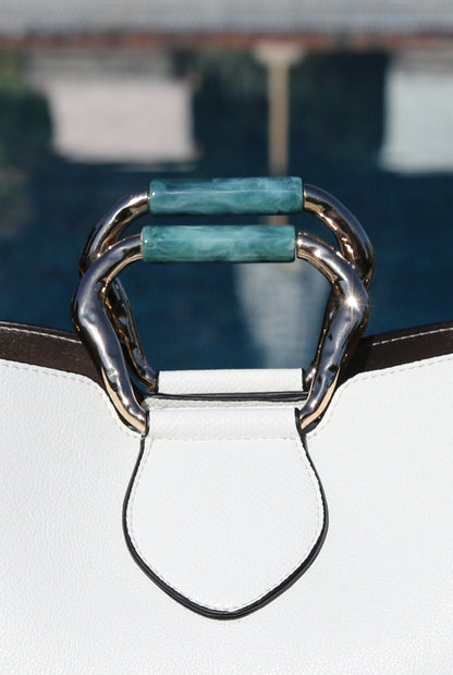 White handbag with green accent handle hardware and gold-tone metal ring