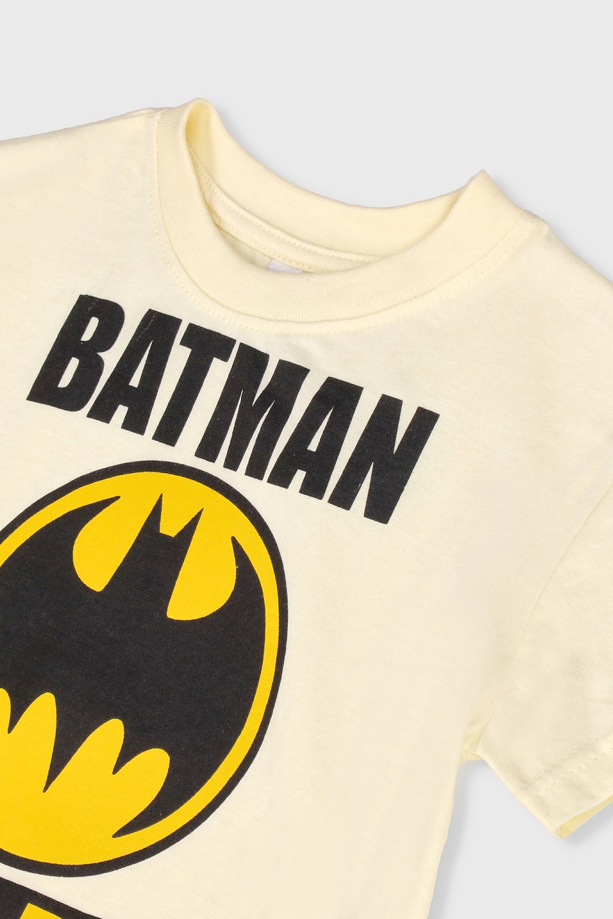 Kids' Batman T-shirt in pale yellow, bold BATMAN print and bat emblem close-up