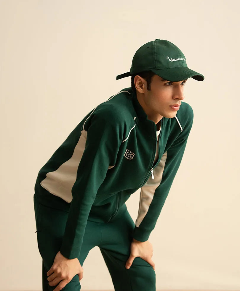 Green tracksuit jacket with zipper and white piping; matching pants with side stripes