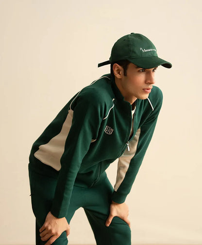 Green tracksuit jacket with zipper and white piping; matching pants with side stripes