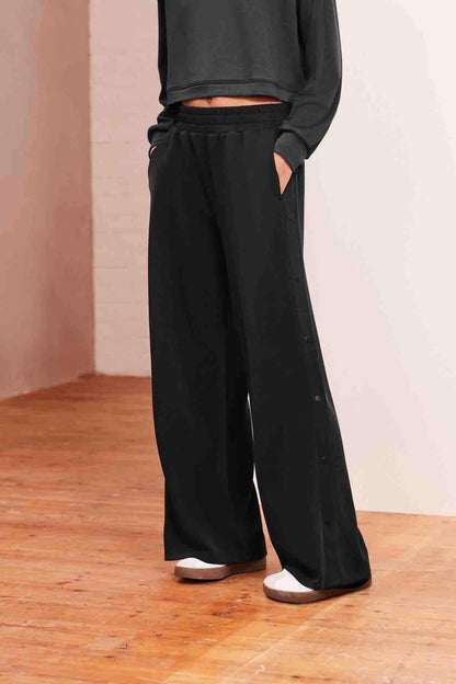 Charcoal grey wide-leg trousers with gathered waist and side buttons