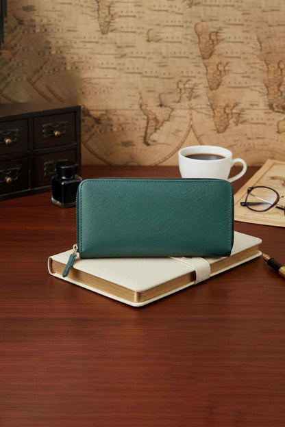 Olive green leather zip wallet with wrist strap on a notebook
