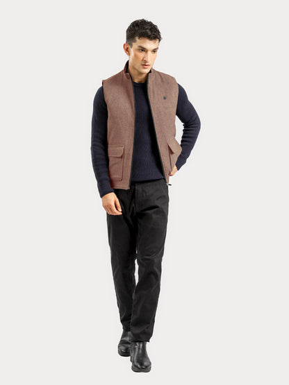 Brumano brown sleeveless vest with flap pockets and button front, worn over sweater