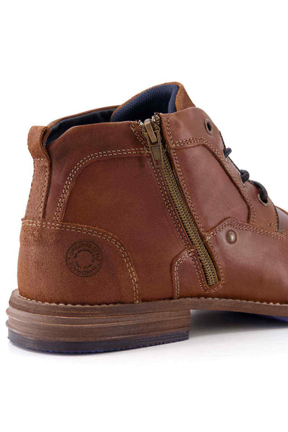 Tan-brown leather ankle boot with side zip, badge detail, and stitched sole.