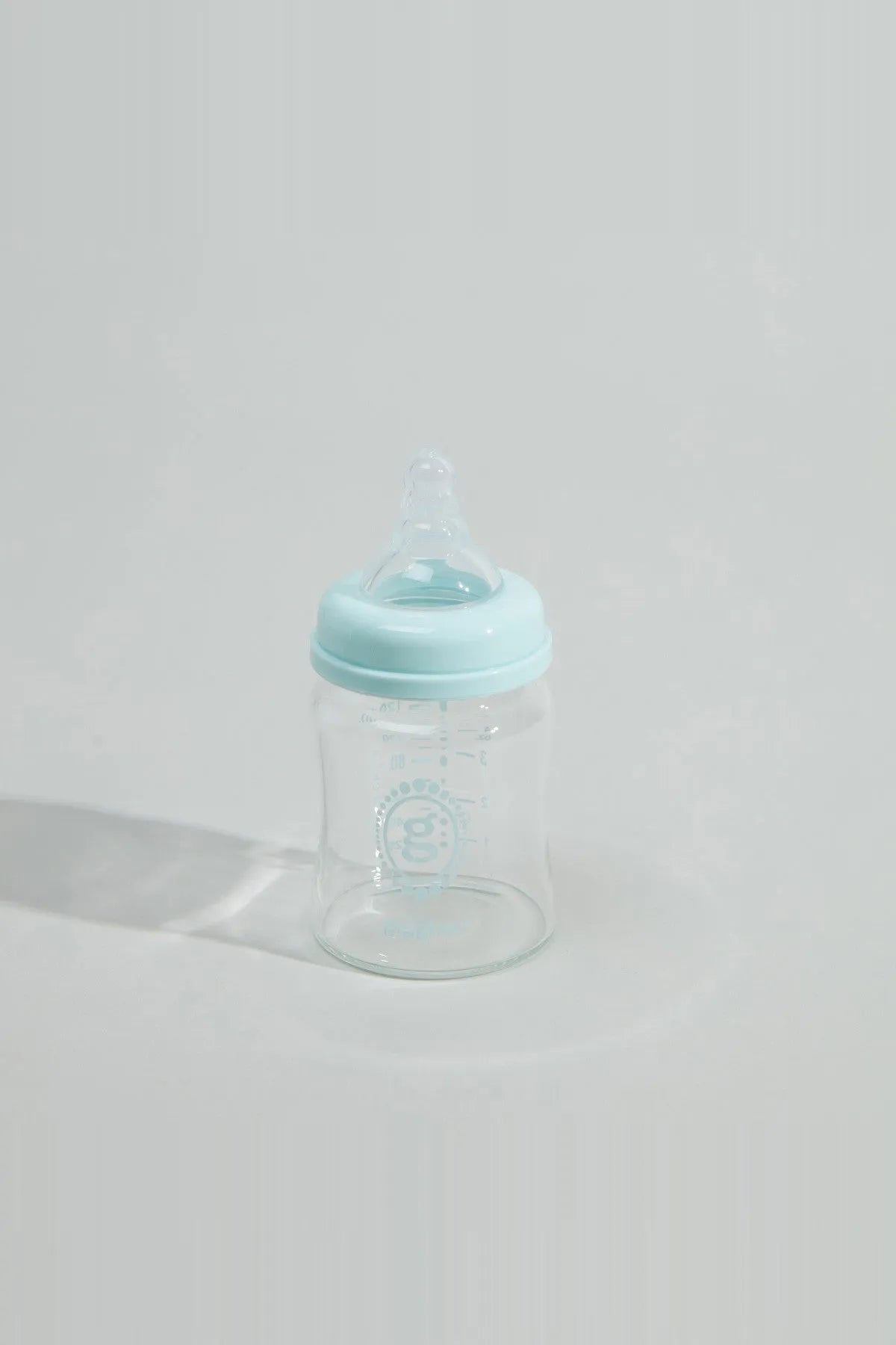 Baby bottle with blue cap and clear body, viewed from front