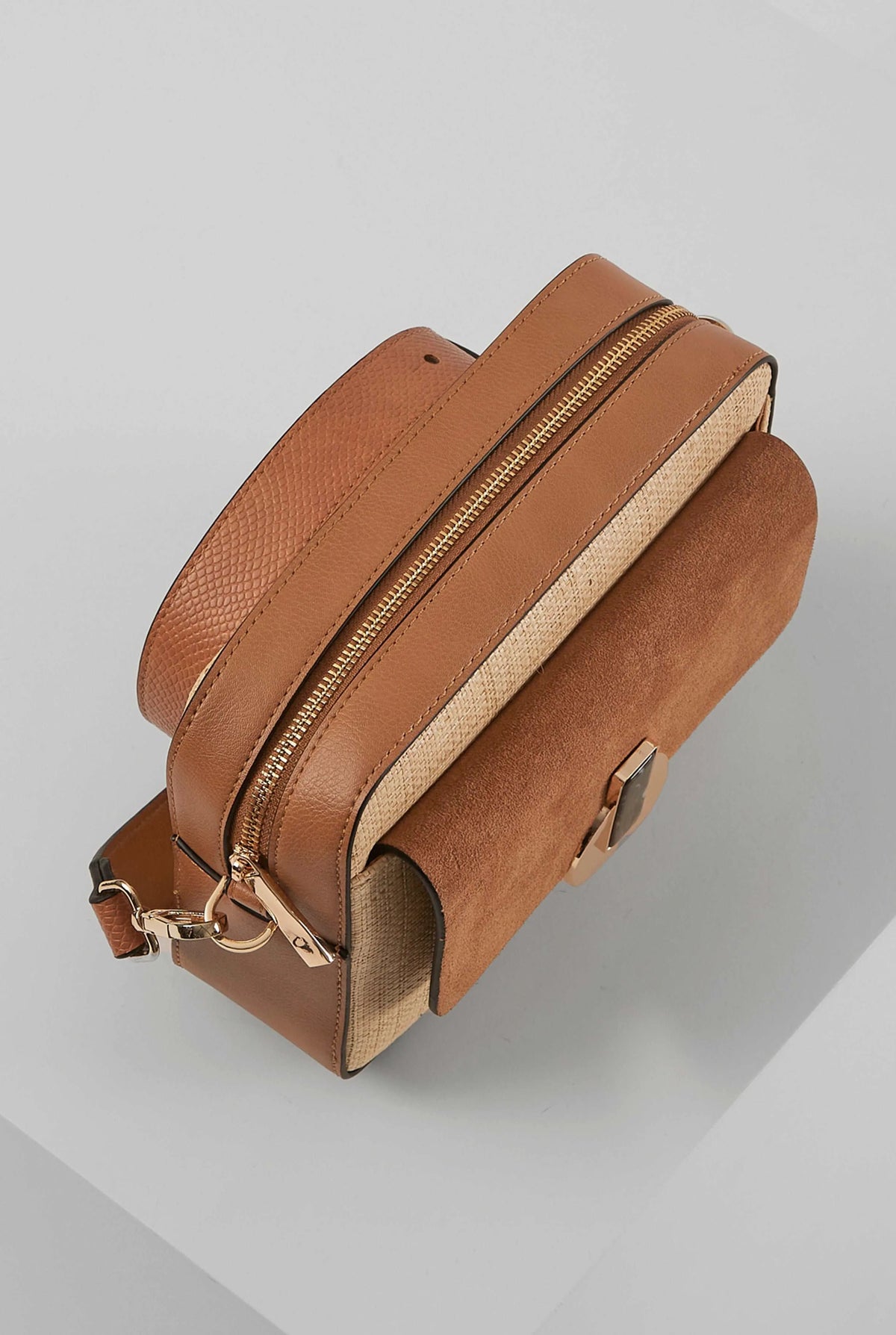 Brown crossbody bag with two-tone flap and top zipper, side view