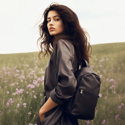 Black backpack with adjustable shoulder straps and front zip pocket, worn on shoulders