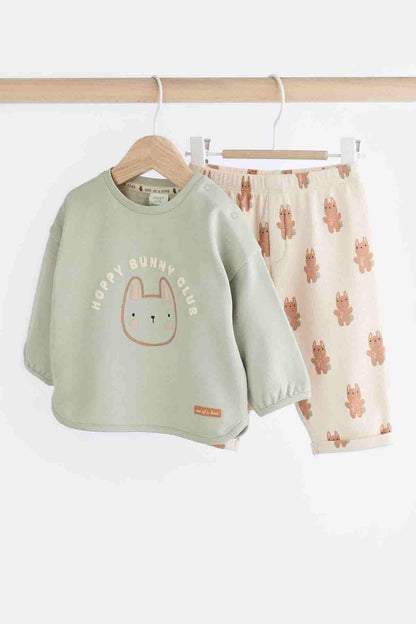 Sage green bunny long-sleeve top and cream bunny print pajama shorts on hangers