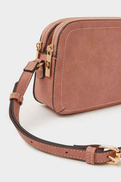 Dusty pink mini crossbody bag with adjustable strap and gold-tone buckles