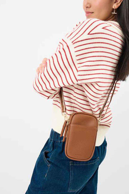 Accessorize tan crossbody bag with adjustable strap and gold hardware, worn at hip