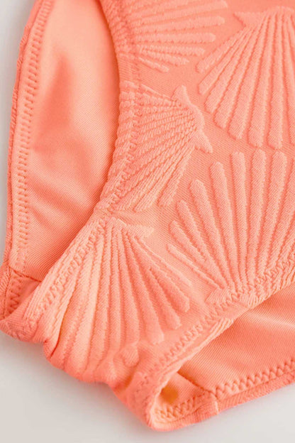 Orange swimsuit fabric close-up with textured fan/leaf pattern and stitched trim