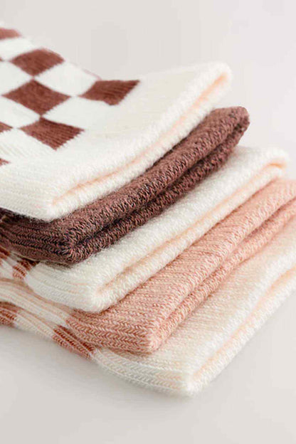 Stack of baby socks in cream, peach, and brown with check and animal prints
