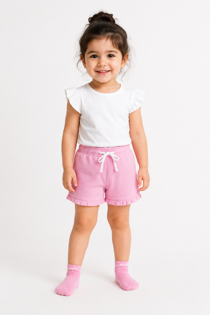 Pink baby shorts with drawstring and ruffle trim, worn with pink socks