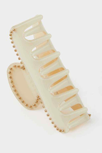 Cream hair claw clip detail with translucent teeth and pearl-like bead border