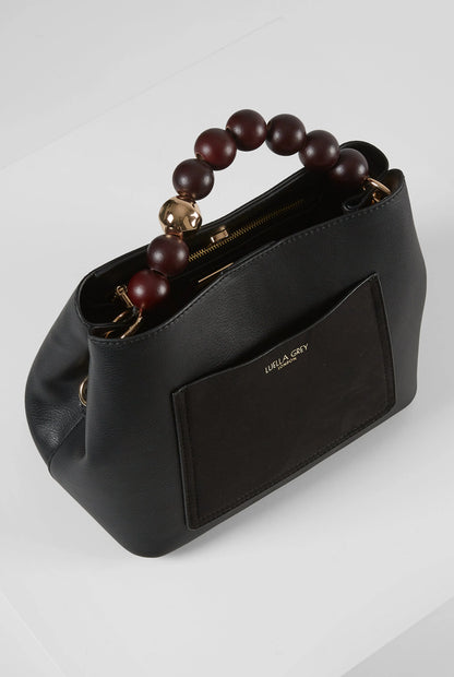 Black handbag side view with brown bead handle and visible gold zipper