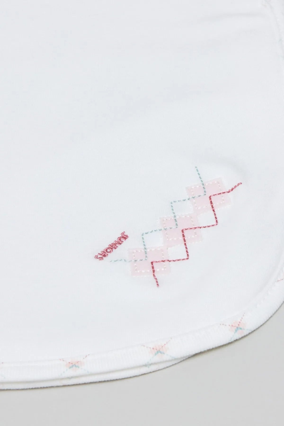 Baby blanket edge close-up with red and blue geometric embroidery stitching