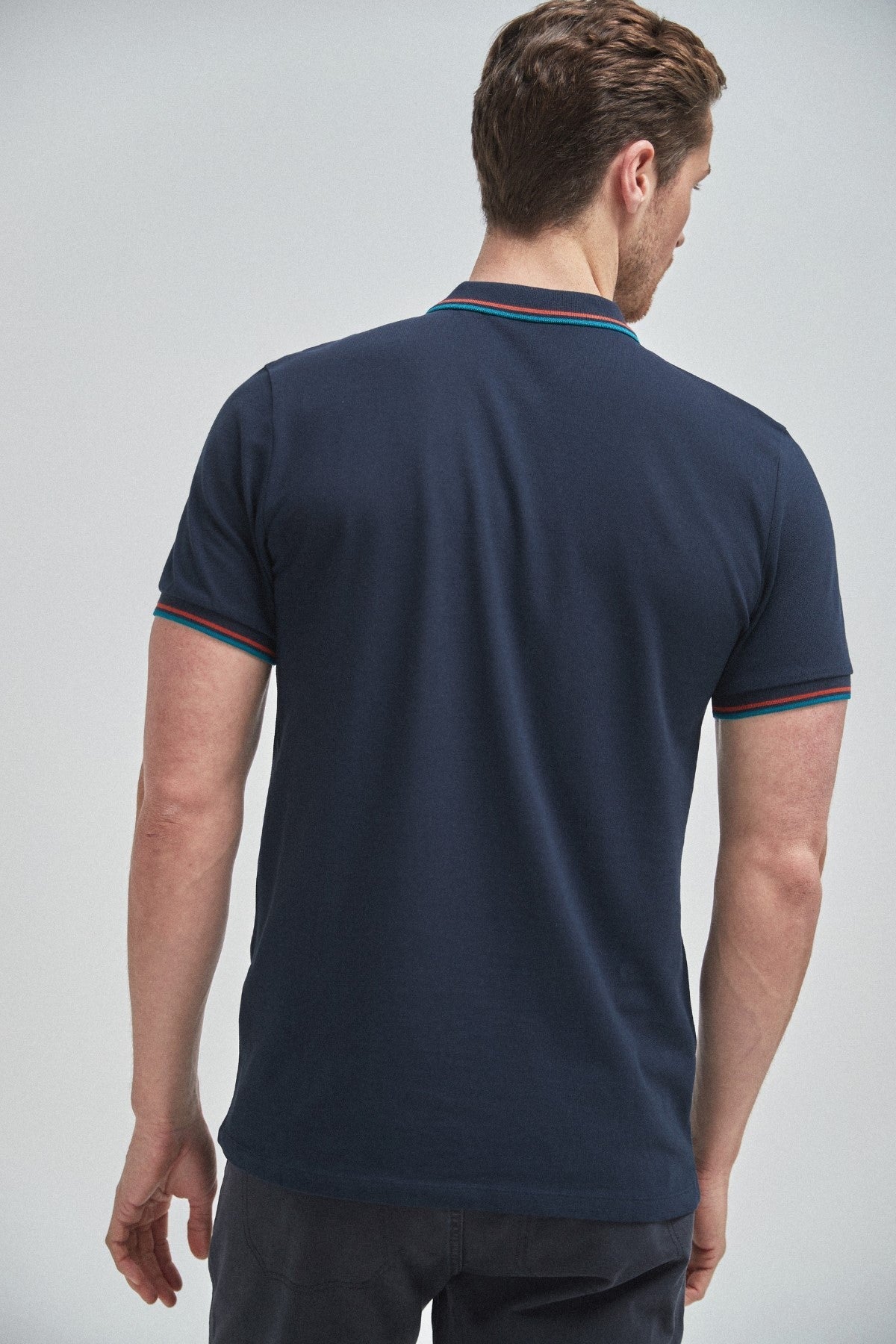 Navy short-sleeve polo shirt with contrast trim at collar and sleeve cuffs (back view)