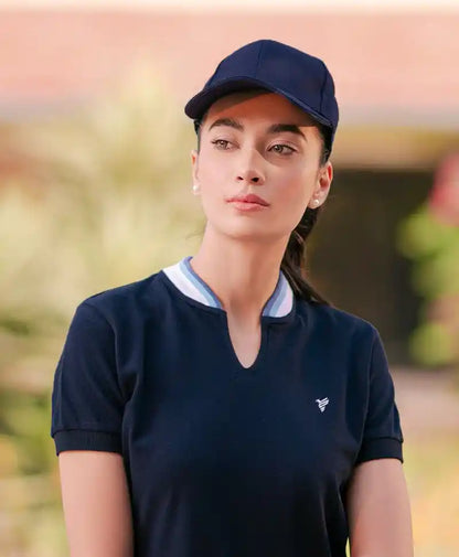 Navy fitted polo shirt with V-neck collar and small chest logo, worn with cap