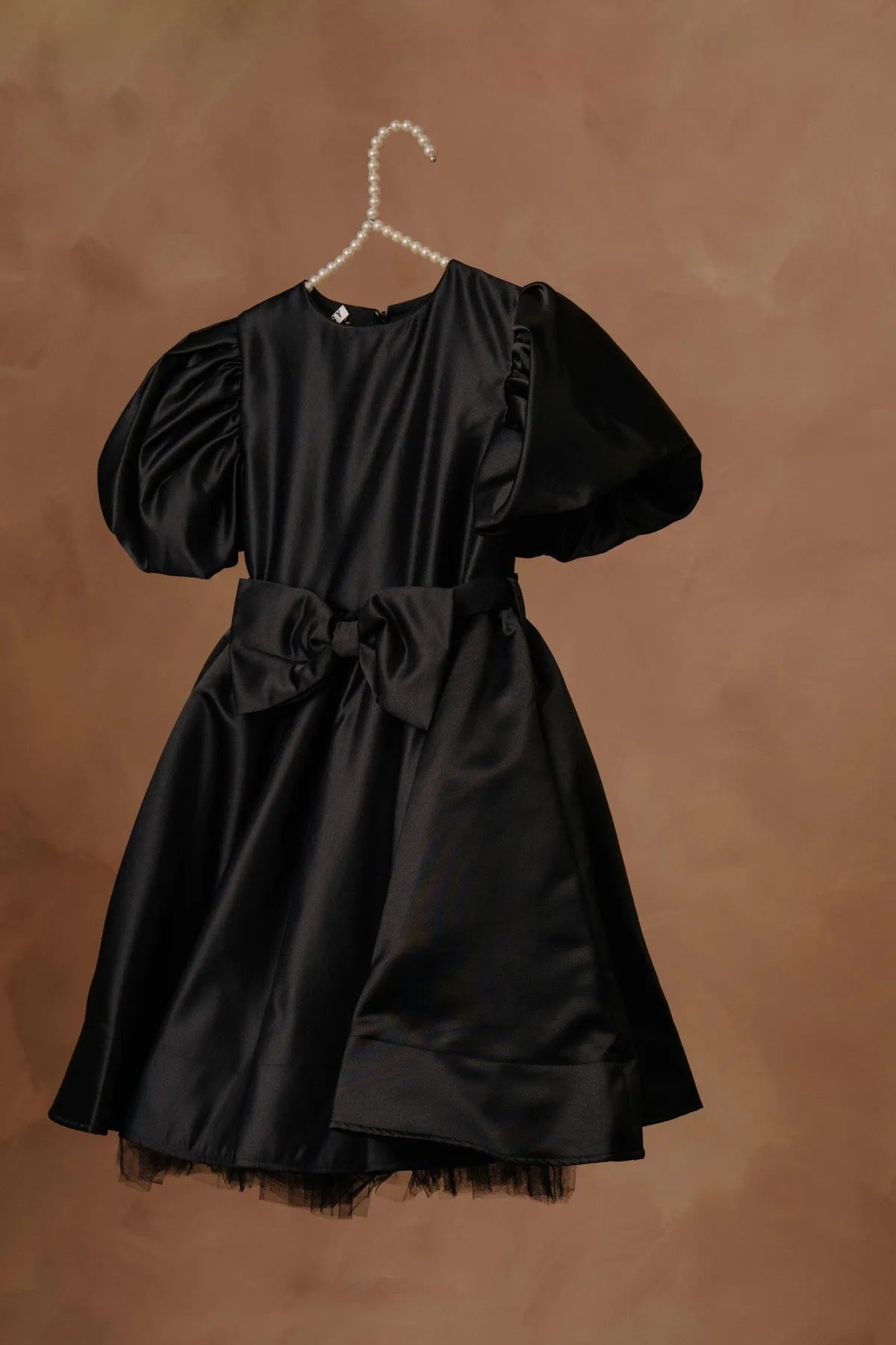 Black puff-sleeve dress with bow waist, flared skirt, and tulle-trim hem