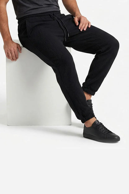 Black jogger pants showing side seam, elastic cuffs, and drawstring waist