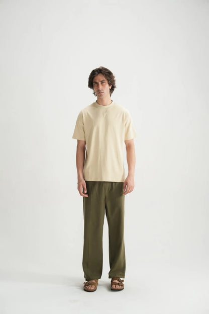Beige short-sleeve crewneck T-shirt with dark green pants, full body front view