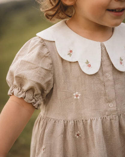 Stone linen-look romper close-up: white collar, embroidered flowers, puff sleeves