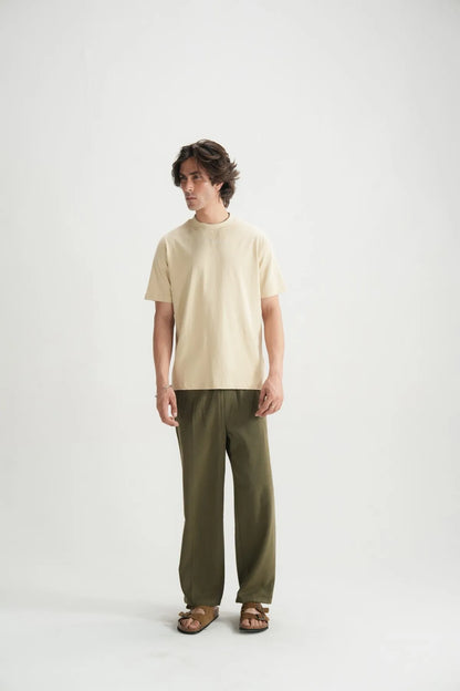 Beige short-sleeve crewneck T-shirt with dark green pants, full body view