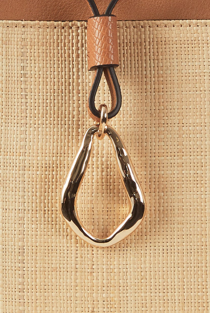 Close-up of woven tote bag with brown leather teardrop keychain charm