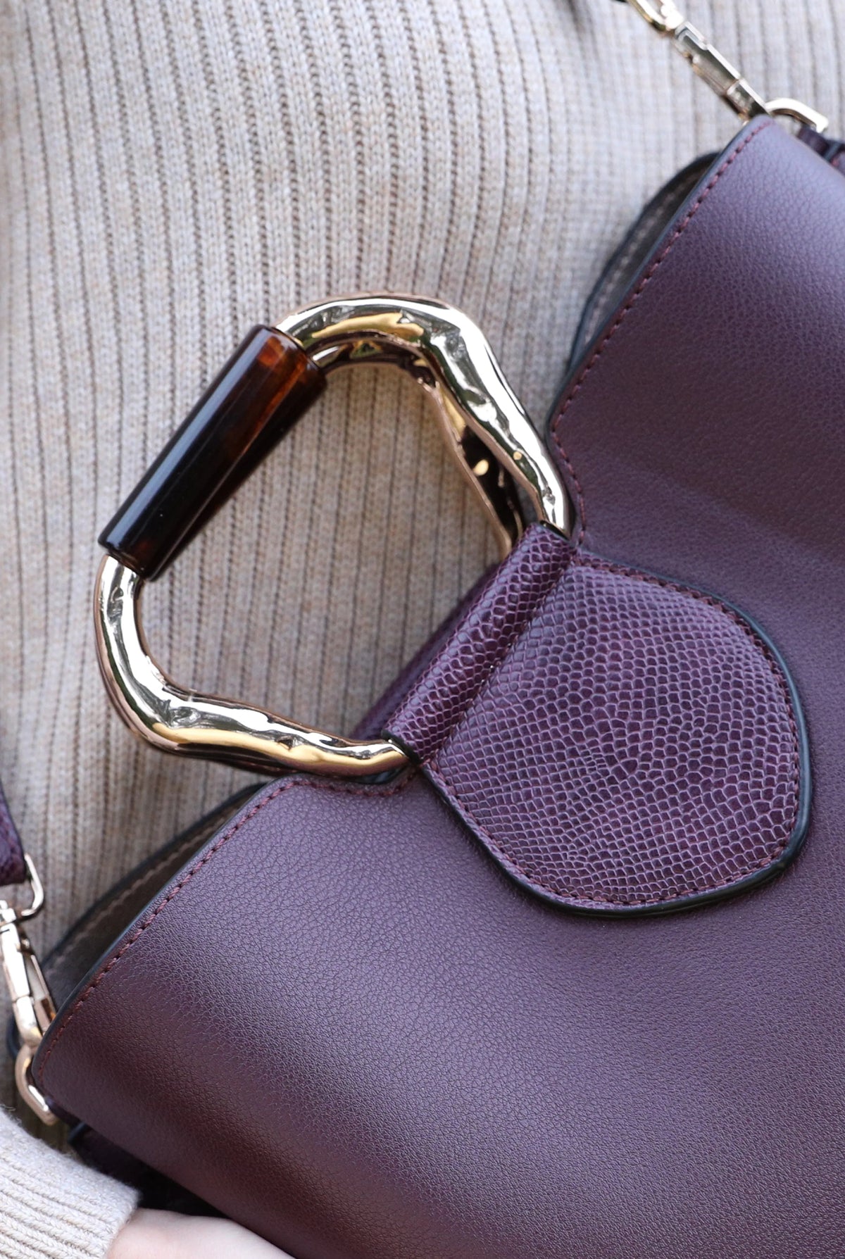 Purple front flap pocket handbag detail with gold-tone clasp and textured side panel