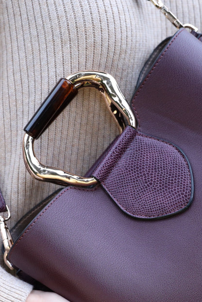 Purple front flap pocket handbag detail with gold-tone clasp and textured side panel